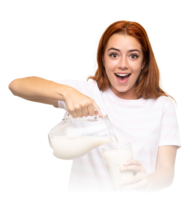 Persona con cabello rojizo y camisa blanca vertiendo leche de una jarra de vidrio en un vaso, con fondo neutro que enfatiza la acción.